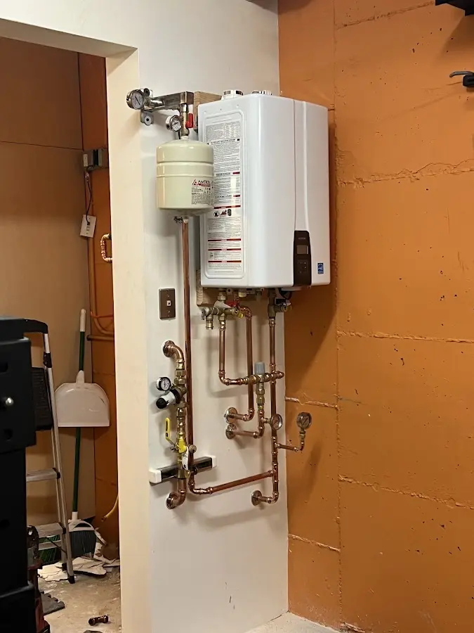 Plumbing technician inspecting water heater connections in Pelham Manor